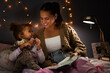 © Micah C/peopleimages.com - Night, book and learning with mother with daughter in bedroom for storytelling, fantasy and smile. Education, fairytale and love with woman reading to girl in family home for bedtime, happy or relax