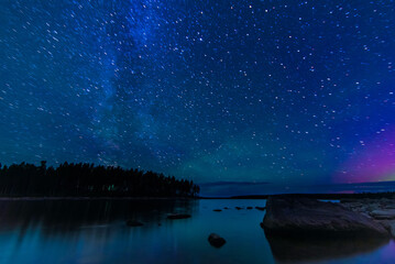 Wall Mural - starry sky with constellations, galaxies, milky way and many stars above water of river with stones 