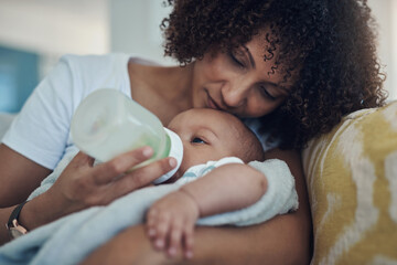 Care, woman feeding her baby with bottle and in living room on the sofa at their home. Family love, drinking or nutrition and black mother feed her newborn child on couch of their house with formula