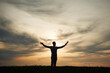 © standret - Silhouette of a man that is in the field at sunset time. Dramatic sky