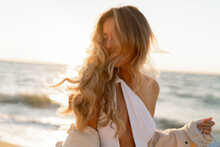 Seductive  Blond Woman In Sexy Swimwear Posing On The Beach In Sunset Light. Prtfect Wavy Hairs, Tan Skim Body. Summer Tropical Mood.