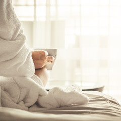 Wall Mural - Woman in white bathrobe and towel lying on sofa and relaxing with tea at the roof.