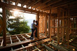 © anatoliy_gleb - Man and woman examining their future wooden frame dwelling nestled in the mountains near forest. Youthful couple at construction site in early morning. Concept of contemporary ecological construction.