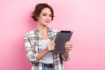 photo of pretty positive lady wear checkered jacket reading modern device empty space isolated pink 