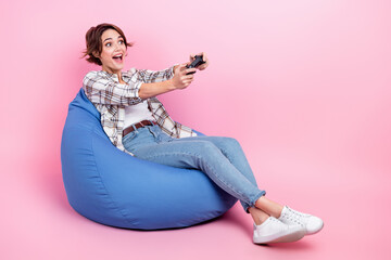 Poster - Full body portrait of positive lady sit comfy bag hold controller play video games look empty space isolated on pink color background