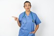 Positive Beautiful doctor woman standing over white studio background with satisfied expression indicates at upper right corner shows good offer suggests to click on link