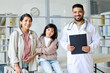 © AnnaStills - Portrait of mom with child smiling at camera together with pediatrician in office