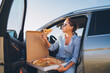 © Soloviova Liudmyla - Midle-aged woman eating just cooked italian pizza sitting on driver car seat during meal break and enjoying sunset light. Auto traveling, fast food eating or car jorney lunch break concept image.