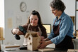 © AnnaStills - Girl with down syndrome using drill to make birdhouse with woman helping her with it in workshop