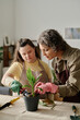 © AnnaStills - Girl with down syndrome learning to transplant green plants in pots together with florist