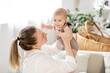 © Any Grant - a young mother holds her little newborn baby in her arms in a bright bedroom, kisses him and admires him, mother's love and care for the child, mom and baby