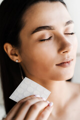 girl with acne stick round acne patch in hands. using acne patches for treatment of pimple and rosac