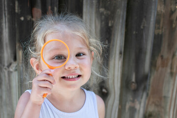 Cute Caucasian smiling toddler girl with magnifying glass. Little Explorer concept. Preschooler with a magnifying glass