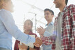 © Katsiaryna - Young startup in casual clothes shaking hands in a modern office space by the window.