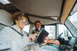 © simona - Happy couple of tourist traveler enjoy drive and live in camper van and using laptop to manage the road trip. Roaming connection during travel. Woman using device inside motorhome in vanlife together