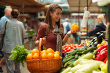Young Woman Buying Fruit In Farmers Market Stall