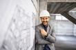 Cheerful caucasian construction engineer standing at building site and smiling to the camera.