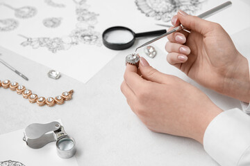 Female jeweler making ring on white table, closeup