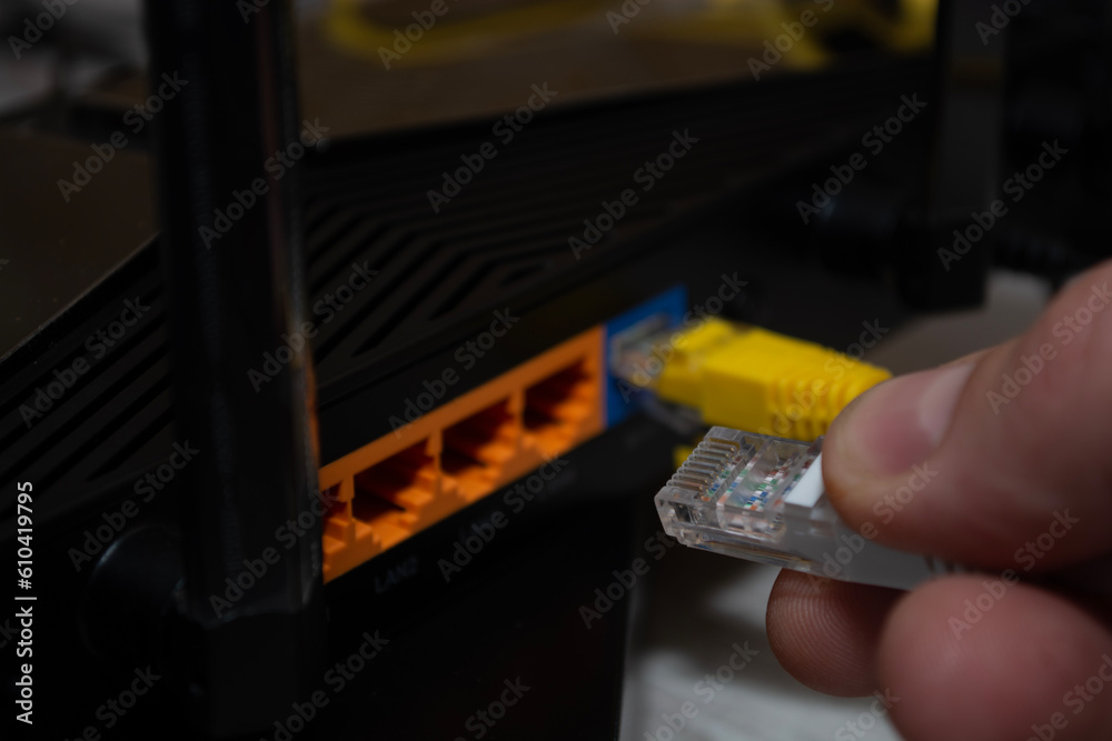 Close-up of a man's hand, fingers connecting a network cable to a ...