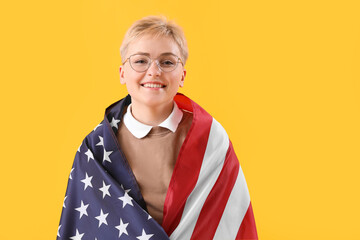 Wall Mural - Young woman with USA flag on yellow background, closeup