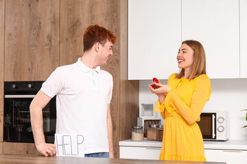 Poster - Young woman proposing to her boyfriend in kitchen