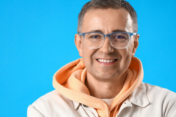 Canvas Print - Mature man in eyeglasses on blue background, closeup