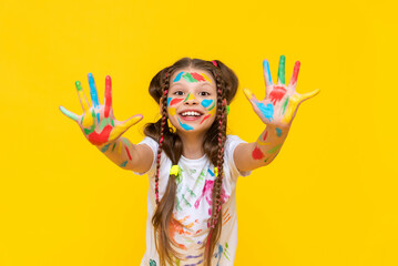 Wall Mural - A cute little schoolgirl with stained hands in paint, A child is engaged in drawing, a girl has stained her hands in paint, A girl shows her hands that she has stained in paint.