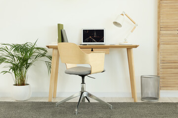 Poster - Cozy workspace with modern laptop on desk and comfortable chair at home