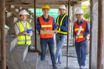 Portrait of experienced diversity team of engineer, architect, worker and safety manager smiling together at the construction site in safety vest and helmet