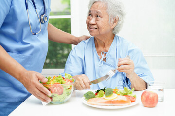 Wall Mural - Asian elderly woman patient eating salmon stake and vegetable salad for healthy food in hospital.