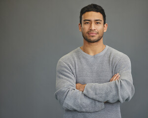 portrait of man in studio with mockup space, arms crossed and confident smile on studio backdrop in 