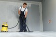 © Serhii - A worker vacuums a room after repairing the floors. Apartment after renovation with a vacuum cleaner.