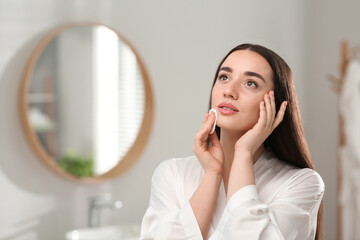 Wall Mural - Beautiful woman removing makeup with cotton pad indoors