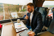 © DusanJelicic - Businessman commuting by train, talking for a video call via laptop,discusses project results and data research