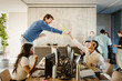 © Maskot - Cheerful entrepreneurs giving high-five while colleagues sitting at desk in creative office