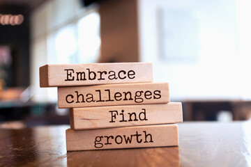 Wall Mural - Wooden blocks with words 'Embrace challenges, find growth'.