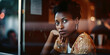 © Marcela Ruty Romero - View through an exterior window of a coffee shop with neon lighting, reflections and glare in the window, of an African woman sitting at a table. Generative AI