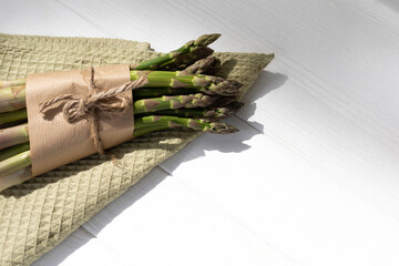 Healthy food background. A fresh asparagus on green kitchen towel on white wooden background. Top view