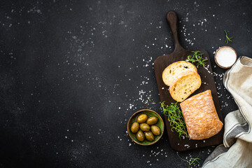 Sticker - Ciabatta bread with olives and herbs on black. Mediterranean food. Top view with copy space.