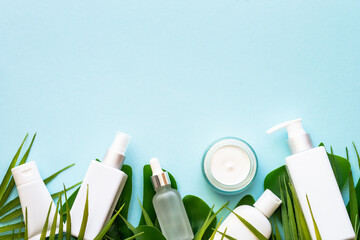 Wall Mural - summer cosmetic, set of cosmetic products with palm leaves on blue. top view.