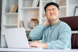 © Ivan - Millennial tired stressed man having a neck pain. Male touching massaging neck sitting at the desk working or studying indoors, suffering from discomfort long hours of sedentary overworking concept