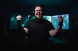 © Denis Yevtekhov - A portrait of a professional gamer standing in front of a screen displaying their victory, radiating joy Generative AI
