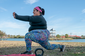 Wall Mural - Young fat woman stretching her body in the park by the lake. Healthy lifestyle