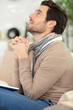 © auremar - faithful middle aged man praying while sitting on sofa