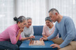 © NewSaetiew - Senior people playing chess board game on sofa. Senior lifestyle at home. Strategy, management and leadership concept.