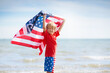 © famveldman - Kids with American flag on beach. 4th of July.