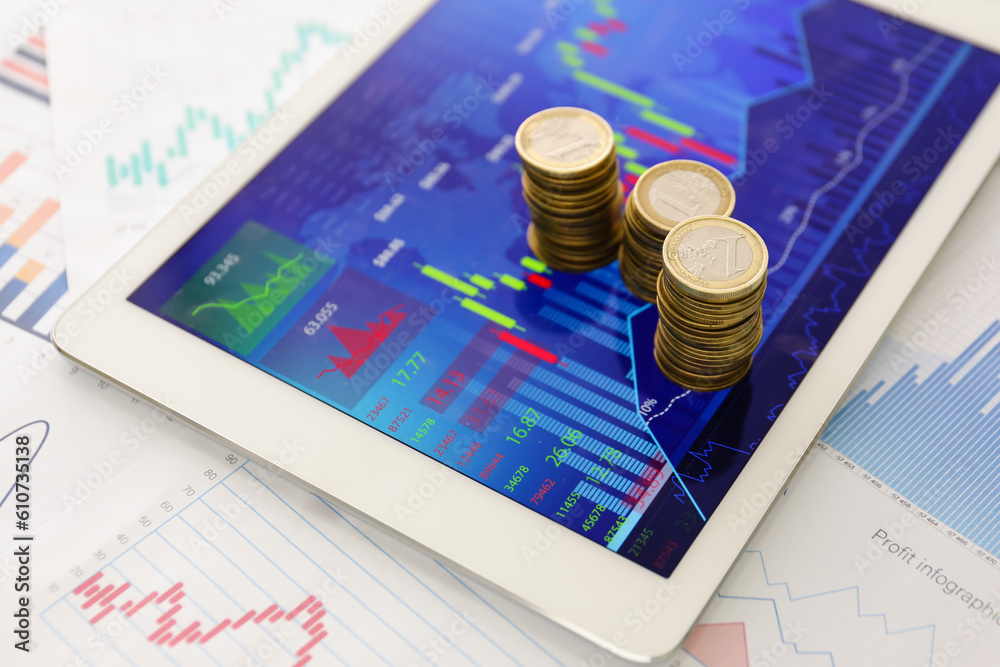 Coins and tablet computer with diagrams of exchange rates, closeup