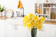 © Pixel-Shot - Vase with blooming narcissus flowers in interior of kitchen, closeup