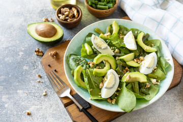 Organic green avocado and spinach salad with eggs, green beans, nuts on a stone table. Healthy food, summer healthy eating. Copy space.