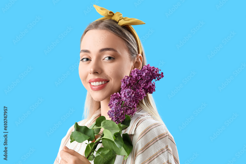 Young woman with lilac flowers on blue background, closeup